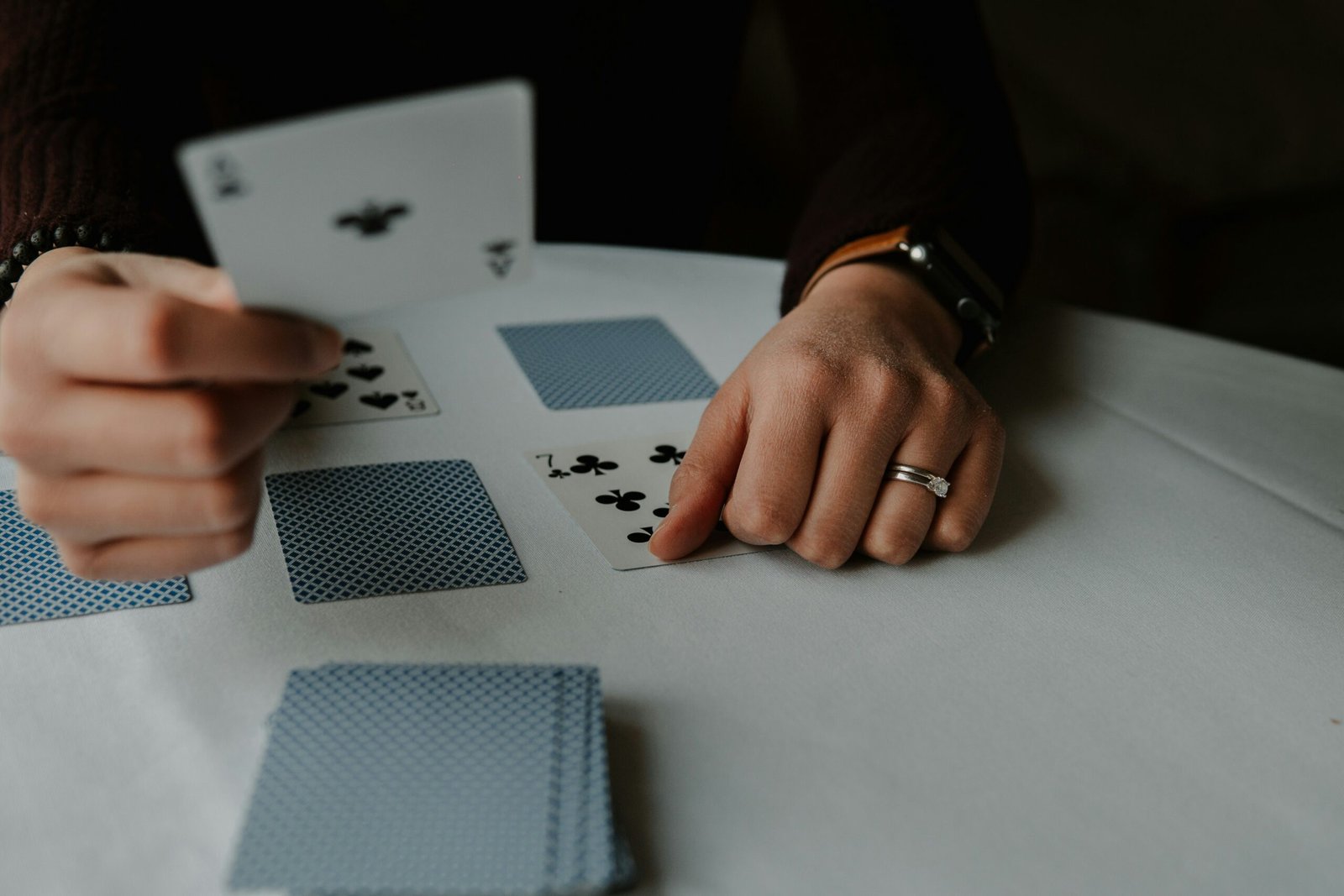 person holding playing cards on white table